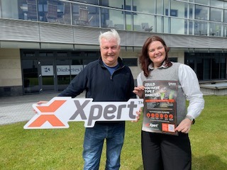 Diabetes Ireland CEO and Amy Doyle holding a Xpert Workwear logo sign outside the Diabetea Ireland offices.